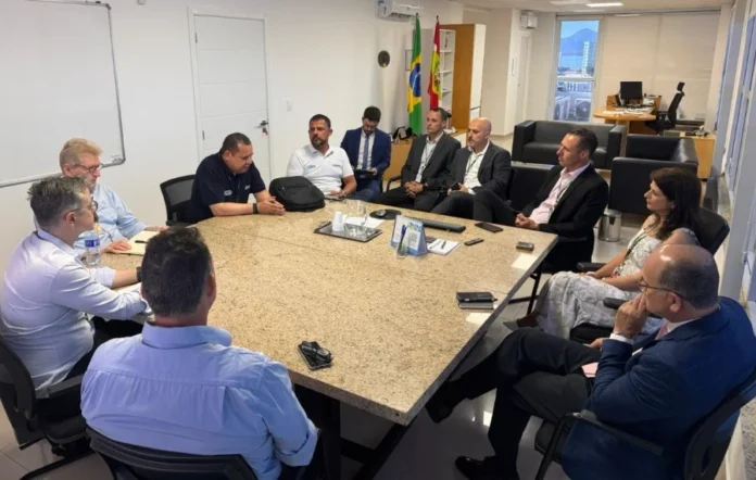 SC atinge 95% de adequação ao novo processo da CNH Comitiva técnica da Senatran e CGU em visita ao Detran/SC. Na imagem, gestores e auditores discutem a adequação dos sistemas para o novo modelo da CNH em uma sala de reuniões oficial.