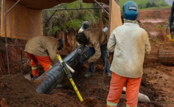 SCGÁS investirá R$ 568 milhões em Santa Catarina até 2030 Trabalhadores com uniformes de segurança e equipamentos de proteção realizam a instalação e soldagem de uma tubulação de gás natural de grande porte em uma vala. A cena ilustra as obras de expansão da infraestrutura da SCGÁS em solo catarinense.