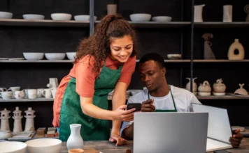 Sebrae/SC aponta passos para empreender com sucesso A imagem mostra dois jovens empreendedores negros em um ateliê de cerâmica, utilizando um celular e um notebook para consultar informações. Esta cena ilustra a importância do planejamento e da busca por conhecimento, que são etapas cruciais para abrir um novo negócio com sucesso em 2026, conforme as orientações estratégicas do Sebrae/SC para o mercado.