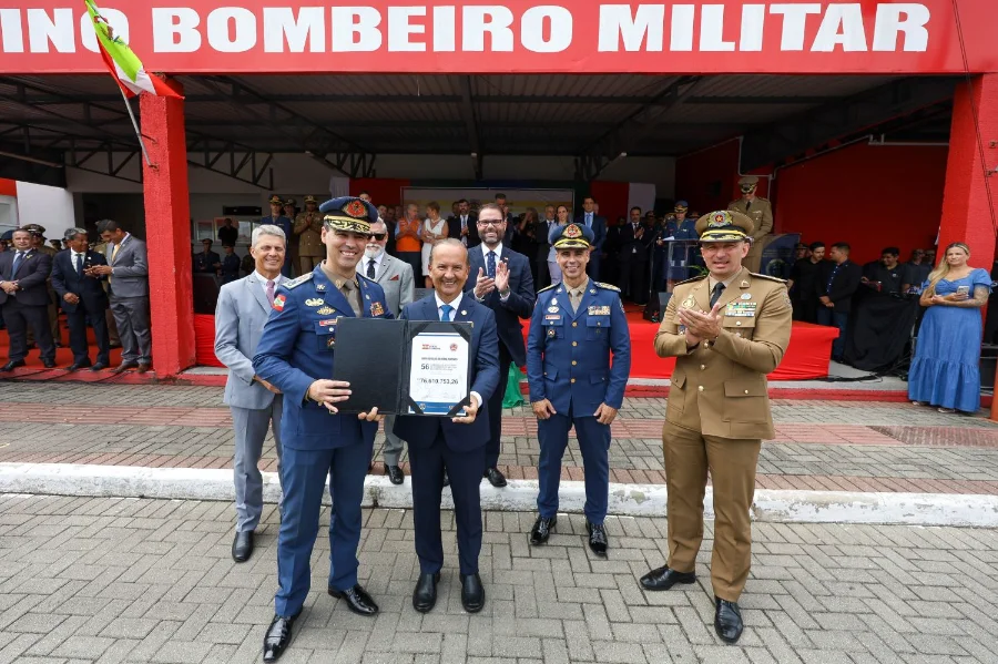 Governador Jorginho Mello, ao centro, segura uma placa simbólica ladeado por oficiais do Corpo de Bombeiros Militar e da Polícia Militar durante solenidade em Florianópolis. O documento em suas mãos exibe o número 