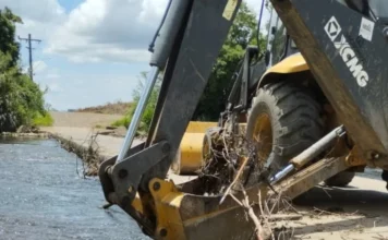 Turvo limpa pontes para prevenir cheias no interior Uma retroescavadeira da Prefeitura de Turvo utiliza sua caçamba para retirar galhos e entulhos acumulados em uma ponte baixa na localidade de São Felipe. A ação visa desobstruir o leito do rio para prevenir alagamentos e garantir a segurança dos moradores durante períodos de chuvas intensas.