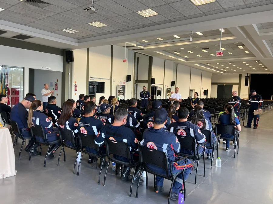 Profissionais do SAMU uniformizados sentados em auditório no Centro de Eventos de Turvo participando de curso de capacitação regional ministrado pelo NEU.