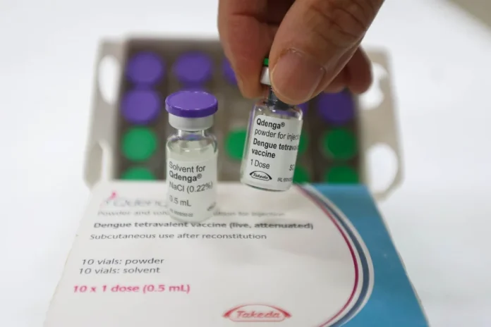 Vacina contra a dengue chega a todas as cidades de SC Mão segura um frasco da vacina Qdenga contra a dengue, com a embalagem e outras doses ao fundo. O imunizante começa a ser distribuído para todos os municípios de Santa Catarina para a vacinação de adolescentes de 10 a 14 anos.