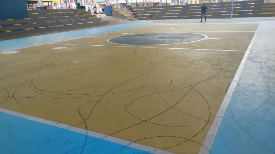 Piso da quadra central de Balneário Arroio do Silva, recém-pintado, coberto por marcas de pneus após ato de vandalismo.