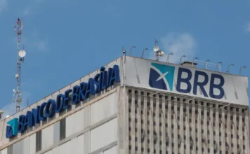 BRB apresenta plano ao BC para recompor capital Foto da fachada superior do edifício sede do Banco de Brasília (BRB), mostrando os letreiros em azul com o nome e a sigla da instituição. O banco está no centro de notícias após entregar um plano de recomposição de capital ao Banco Central para enfrentar problemas de liquidez.