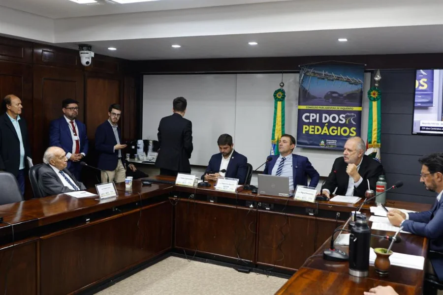 Registro fotográfico da reunião da CPI dos Contratos de Concessão das Rodovias Estaduais na Assembleia Legislativa do RS. Deputados estão sentados ao redor de uma mesa de madeira em formato de 