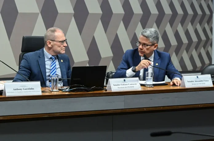 CPI avalia convite a ministros do STF e Banco Master O senador Alessandro Vieira (à direita), relator da CPI do Crime Organizado, sentado à mesa diretora durante uma sessão da comissão no Senado Federal. Ele é o autor do requerimento para o depoimento de TH Joias, mencionado na matéria.