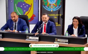 Câmara de Sombrio moderniza comunicação em sessões de 2026 Captura de tela da nova transmissão em alta definição da Câmara Municipal de Sombrio. A imagem mostra o presidente Jonas D'Ávila ao centro da mesa diretora, ladeado por dois parlamentares, durante a sessão ordinária realizada em 09 de fevereiro de 2026. O registro apresenta a nova identidade visual e a clareza de imagem implementada pelo sistema de comunicação atualizado.