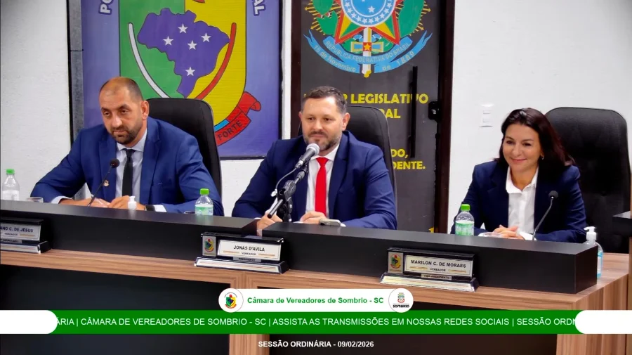 Captura de tela da nova transmissão em alta definição da Câmara Municipal de Sombrio. A imagem mostra o presidente Jonas D'Ávila ao centro da mesa diretora, ladeado por dois parlamentares, durante a sessão ordinária realizada em 09 de fevereiro de 2026. O registro apresenta a nova identidade visual e a clareza de imagem implementada pelo sistema de comunicação atualizado.