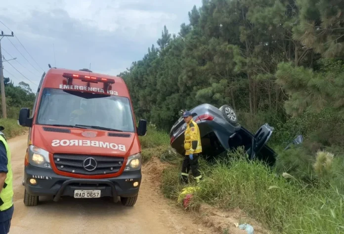 Carro capota após colisão na Zona Norte do Rincão Registro do atendimento de ocorrência de trânsito no Balneário Rincão, mostrando um Volkswagen Voyage capotado à margem da via e a unidade de emergência dos bombeiros posicionada para o socorro.
