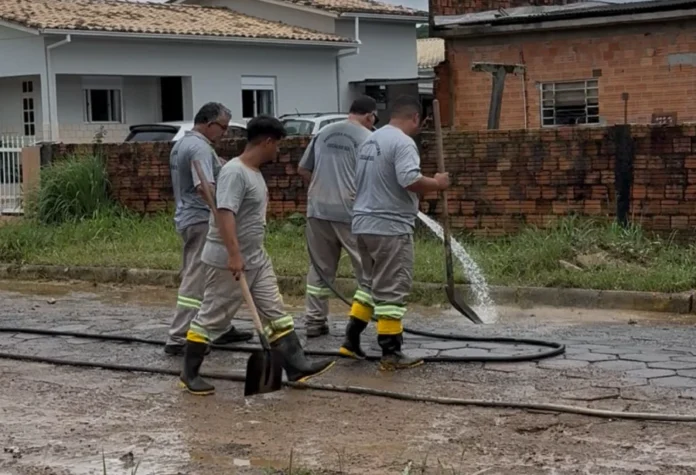 Cocal do Sul prepara decreto de emergência após chuvas Equipe municipal realiza a retirada de lodo e entulhos de via pavimentada em Cocal do Sul, em ação de recuperação urbana após o transbordamento do Rio Tigre.