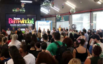 Colaboradores da Unesc celebram abertura do ano letivo Uma grande concentração de colaboradores da Unesc reunidos em um ambiente interno do campus durante a recepção institucional de 2026. Ao fundo, um telão digital exibe a mensagem "Sejam Bem-vindos! Encontre aqui o melhor de você", acompanhada da logomarca da universidade. Próximo ao telão, destaca-se um totem com a palavra "INCRÍVEIS", em alusão ao reconhecimento da instituição no ranking de melhores lugares para trabalhar. O público, composto por homens e mulheres, aparece de costas e de perfil, voltado para a frente onde ocorre a cerimônia de abertura.