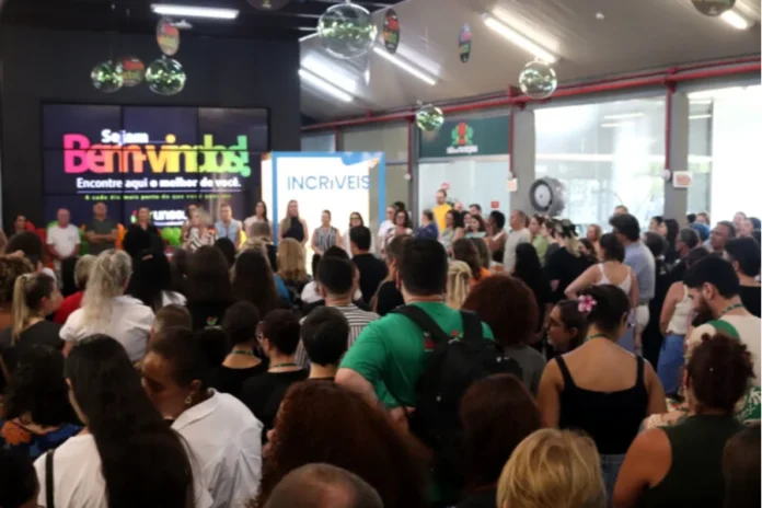 Colaboradores da Unesc celebram abertura do ano letivo Uma grande concentração de colaboradores da Unesc reunidos em um ambiente interno do campus durante a recepção institucional de 2026. Ao fundo, um telão digital exibe a mensagem "Sejam Bem-vindos! Encontre aqui o melhor de você", acompanhada da logomarca da universidade. Próximo ao telão, destaca-se um totem com a palavra "INCRÍVEIS", em alusão ao reconhecimento da instituição no ranking de melhores lugares para trabalhar. O público, composto por homens e mulheres, aparece de costas e de perfil, voltado para a frente onde ocorre a cerimônia de abertura.