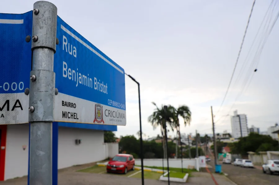Placa azul de identificação urbana em primeiro plano com os dizeres 