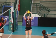 Criciúma recebe Ceará no Ginásio da Unesc nesta terça Uma jogadora da equipe de voleibol Mampituba/FME Criciúma/Radar/Unesc, vestindo uniforme preto e vermelho com patrocinadores, está em quadra realizando um toque com as duas mãos acima da cabeça durante uma partida. Ela está perto da rede, e outras jogadoras podem ser vistas ao redor. O ginásio possui arquibancadas verdes e banners de patrocinadores ao fundo, incluindo a marca da Unesc.