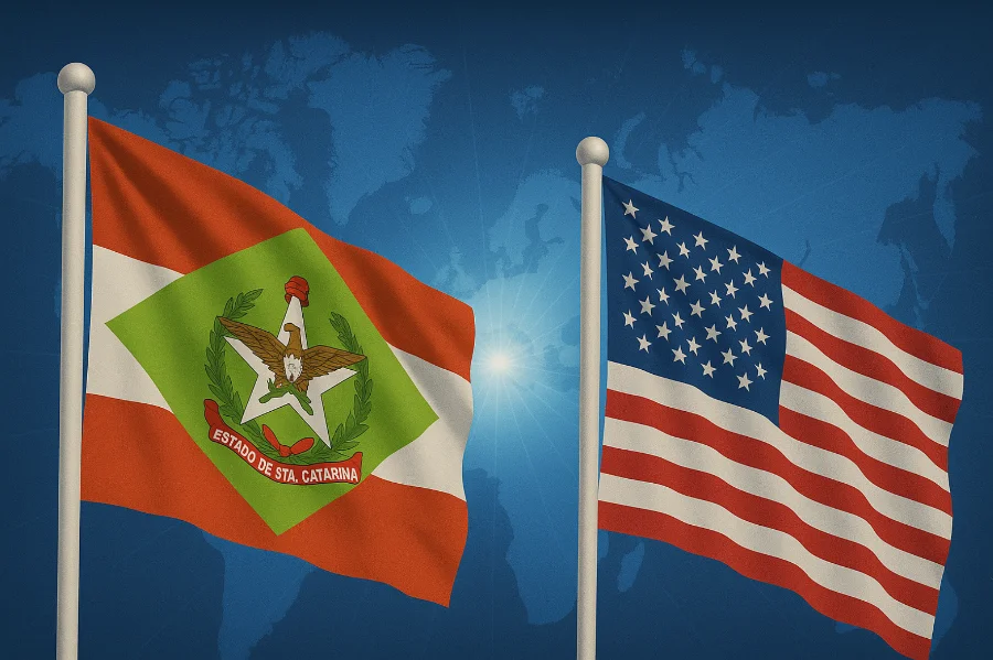 Duas bandeiras hasteadas lado a lado: à esquerda, a bandeira do Estado de Santa Catarina e, à direita, a bandeira dos Estados Unidos. Elas aparecem em destaque contra um fundo azul que exibe um mapa-múndi estilizado com um ponto de luz central.
