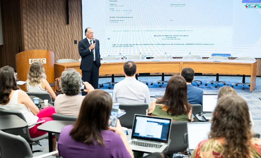 O presidente da FIESC, Gilberto Seleme, discursa durante o workshop sindical para executivos na sede da Federação, em Florianópolis. A imagem mostra o auditório com participantes e uma tela ao fundo.