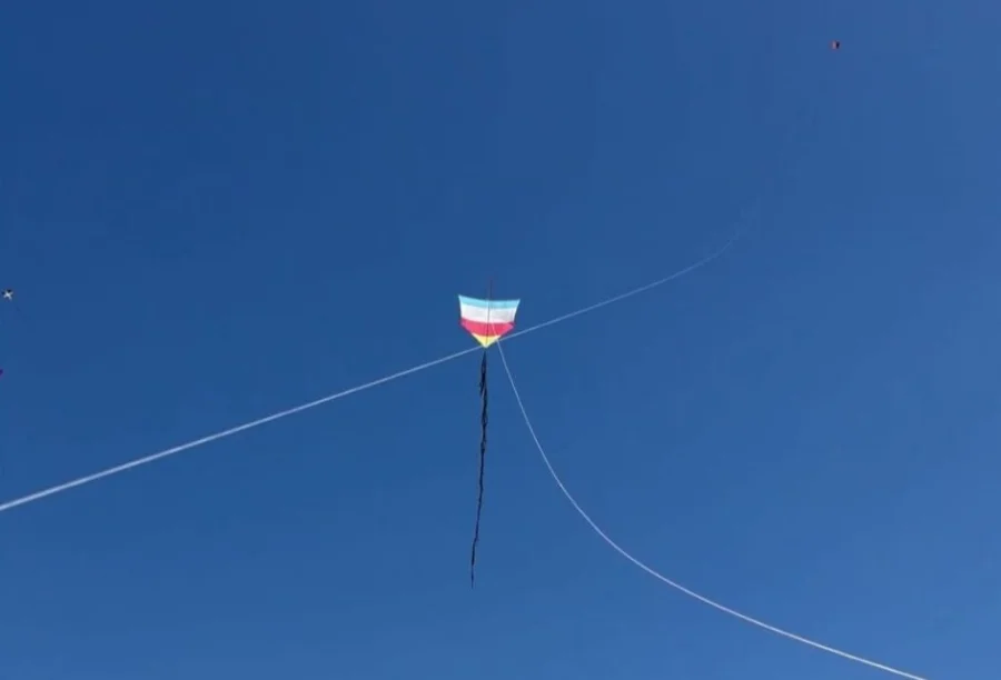 Festival de Pipas reúne famílias no Morro dos Conventos Uma pipa colorida nas cores azul, branco, vermelho e amarelo voa solitária contra um céu de azul intenso e sem nuvens. A pipa possui uma longa cauda preta que balança ao vento, e linhas brancas de sustentação atravessam a imagem em diagonal, capturando um momento de lazer durante o Festival de Pipas no Morro dos Conventos, em Araranguá.