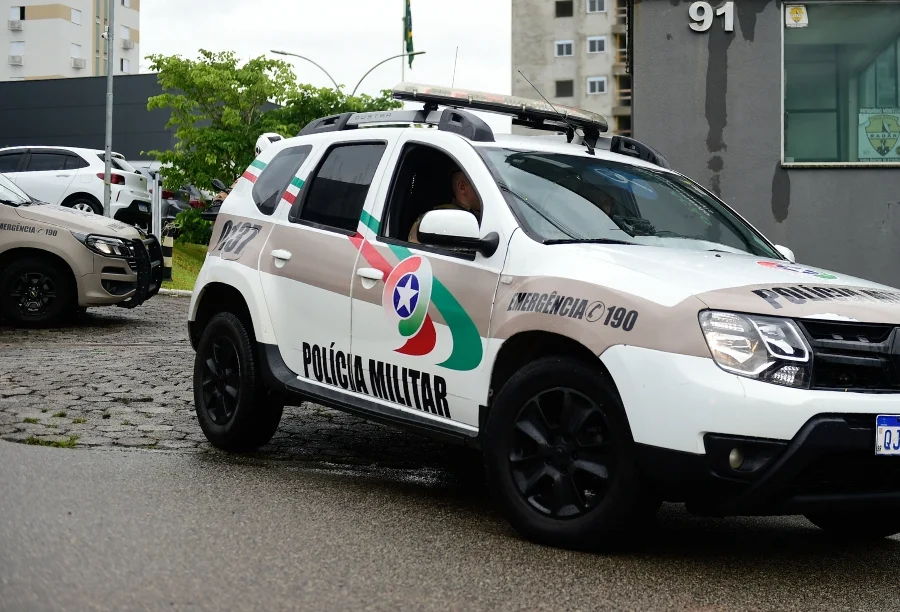 Hidrômetro é furtado de centro educacional em Criciúma Viatura da Polícia Militar de Santa Catarina (PMSC), modelo SUV de cor branca com grafismos em bege, verde e vermelho, estacionada em uma rua pavimentada. No detalhe lateral, lê-se