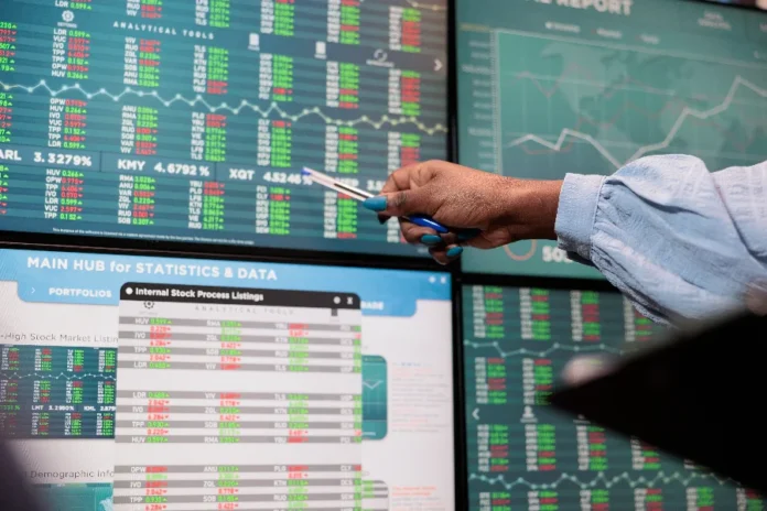Ibovespa bate recorde e aproxima-se de 186 mil pontos Uma pessoa analisa gráficos e dados financeiros em múltiplas telas, ilustrando o acompanhamento do mercado em um dia de recorde histórico na bolsa de valores brasileira.