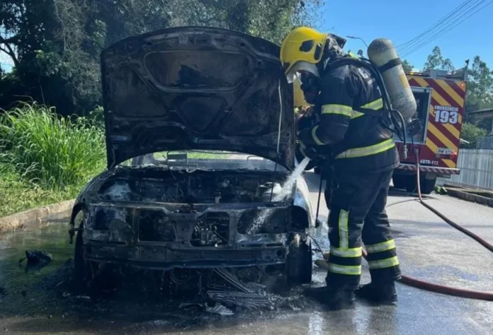 Incêndio destrói Saveiro em via pública de Criciúma Bombeiro realiza o resfriamento e a extinção de incêndio em um veículo utilitário no bairro Verdinho, em Criciúma. A imagem foca no combate direto às chamas que consumiram a parte frontal do automóvel.
