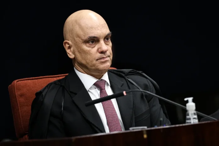 Moraes enfrenta resistência no STF após operação da PF Imagem focada no ministro Alexandre de Moraes, relator de inquéritos sensíveis no STF, durante exercício de suas funções. A composição ressalta sua figura centralizadora no tribunal, tema principal da matéria que aborda a crescente desconfiança entre os ministros do colegiado.
