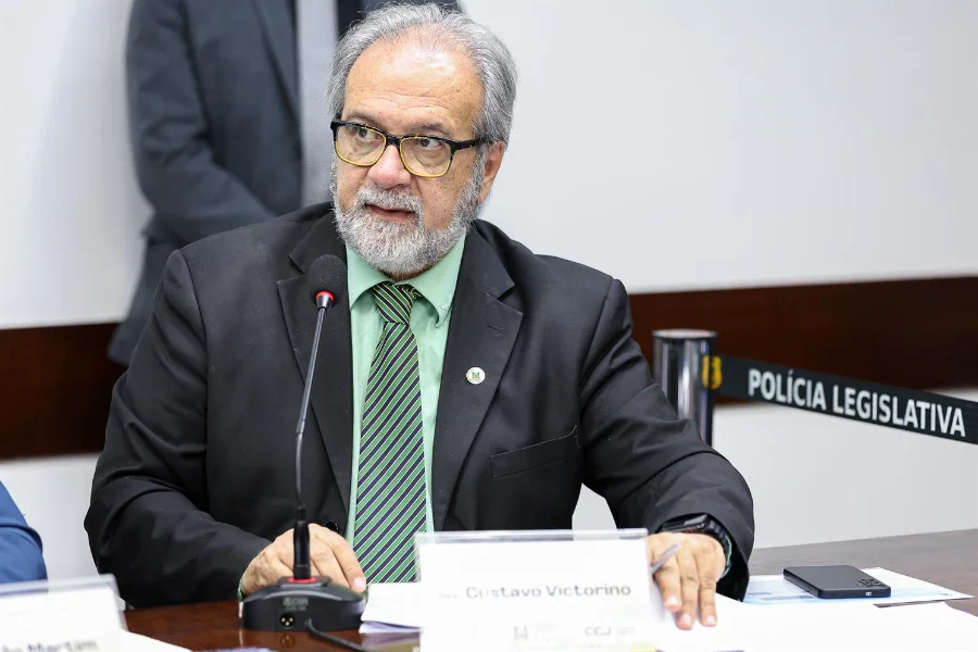 O deputado Gustavo Victorino (Republicanos), autor do PL 45/2026 que cria a Política Estadual de Proteção à Identidade Digital da Advocacia para combater golpes em precatórios no RS, é visto discursando em uma comissão legislativa, gesticulando com as mãos sobre a mesa.