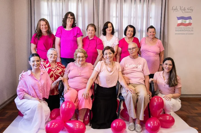 Siderópolis é destaque em mostra estadual de saúde Mulheres participantes de uma ação de conscientização do Outubro Rosa em Siderópolis reunidas para uma foto comemorativa, destacando a união na prevenção do câncer de mama.
