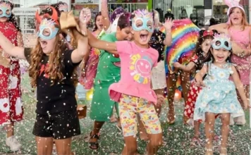 Sombrio Moda Shopping realiza Carnaval Infantil no dia 15 Grupo de crianças sorridentes celebrando o Carnaval no Sombrio Moda Shopping. Elas usam máscaras coloridas e fantasias enquanto se divertem em meio a uma chuva de confetes, ilustrando o clima festivo e de convivência do evento Folia Kids.