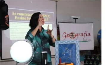 Unesc abre matrículas para licenciaturas com bolsas de 100% Imagem demonstrativa de uma aula prática de Licenciatura na Unesc. Uma docente utiliza modelos de constelações e um globo terrestre para ensinar Geografia, ilustrando a metodologia de ensino dinâmica dos cursos que estão com bolsas de estudo de 100% disponíveis.