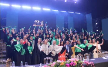 Unesc forma novos profissionais de saúde em Criciúma Formandos dos cursos de Farmácia, Fisioterapia e Tecnologia em Estética e Cosmética da Unesc celebram no palco do AM Master Hall. O grupo veste becas pretas com faixas e capelos verdes, erguendo com entusiasmo seus diplomas. Ao fundo, luzes de palco azuis iluminam o ambiente, e à frente, uma mesa decorada com flores rosas e brancas compõe o cenário da solenidade.