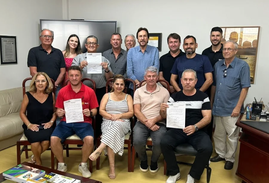 Grupo de autoridades e representantes da comunidade de Araranguá, incluindo o prefeito Cesar Cesa, posam para foto oficial segurando o documento da Ordem de Serviço para a construção da nova praça pública no bairro Vila São José.