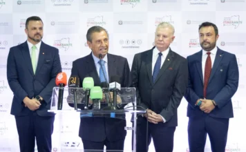 Alesc Itinerante inicia debates regionais em Curitibanos Coletiva de imprensa na Alesc Itinerante em Curitibanos com o Deputado Julio Garcia (Presidente da Alesc, centro, falando). Ao seu lado estão os deputados da bancada serrana: Marcius Machado (extrema esquerda), Nilso Berlanda (segundo à direita) e Lucas Neves (extrema direita), todos em um púlpito com microfones e backdrop do evento Alesc Itinerante.