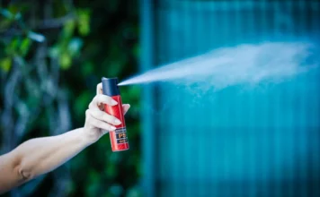 Alesc aprova spray de pimenta para mulheres sob proteção Mão feminina segurando e acionando um frasco de spray de pimenta vermelho e preto, expelindo gás. Uma representação do dispositivo de defesa pessoal que será fornecido a mulheres sob medida protetiva em Santa Catarina após aprovação da Alesc.