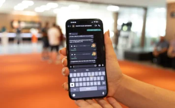 Alesc lança campanha contra golpe do falso advogado em SC Close-up de uma mão segurando um smartphone em um ambiente público desfocado. A tela do aparelho exibe uma conversa de WhatsApp com o contato salvo como "GOLPE FALSO ADVOGADO". As mensagens mostram um criminoso solicitando o pagamento de uma taxa de R$ 5.000,00 via PIX para a liberação de um suposto processo judicial.
