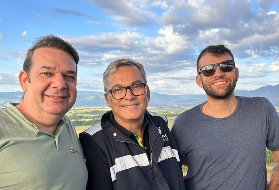 Representantes da ANAC, incluindo o diretor Luiz Ricardo de Souza Nascimento (ao centro, vestindo colete oficial), posam durante voo de balão em Praia Grande, SC. A imagem destaca a fiscalização de segurança e a aplicação das novas regras do balonismo durante a Expocanyon.