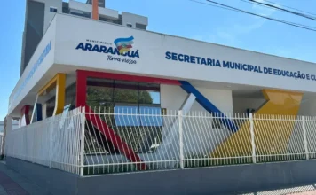 Araranguá convoca aprovados na educação para 10 cargos Fachada lateral do prédio da Secretaria Municipal de Educação e Cultura de Araranguá, Santa Catarina. A edificação branca possui arquitetura moderna com detalhes geométricos em vermelho, amarelo e azul, exibindo o logotipo oficial do Município de Araranguá.