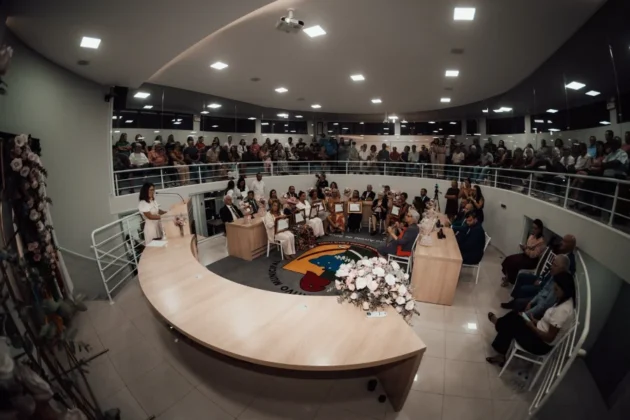 Vista panor&acirc;mica de grande angular do plen&aacute;rio da C&acirc;mara de Vereadores de Balne&aacute;rio Arroio do Silva, com oradora, plateia e galeria de p&uacute;blico lotada para a Sess&atilde;o Solene do Trof&eacute;u Luc&iacute;lia da Silva Borges.