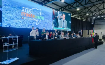 CCJ aprova reconhecimento do Tiro de Laço como esporte em SC Mesa diretora da ALESC Itinerante em Curitibanos, Santa Catarina, durante sessão da Comissão de Constituição e Justiça (CCJ). Deputados estaduais SC participam de reunião parlamentar com telão ao fundo exibindo o logotipo da Assembleia Legislativa.