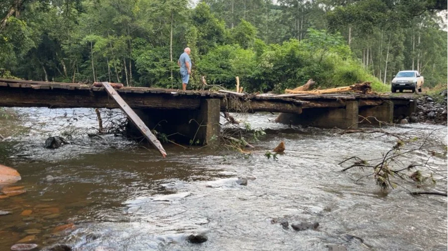 Ponte de madeira com estrutura danificada após fortes chuvas e enxurrada em Jacinto Machado, no interior de Santa Catarina, evidenciando os estragos na infraestrutura rural.