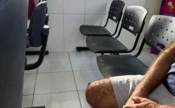 Cocal do Sul registra 4 mil faltas em exames e consultas Fileira de cadeiras de plástico pretas vazias em uma sala de espera de uma unidade de saúde municipal em Cocal do Sul, representando as faltas em consultas e exames. Um homem está sentado no primeiro plano.