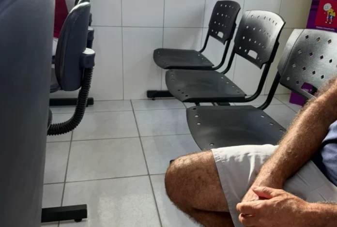 Cocal do Sul registra 4 mil faltas em exames e consultas Fileira de cadeiras de plástico pretas vazias em uma sala de espera de uma unidade de saúde municipal em Cocal do Sul, representando as faltas em consultas e exames. Um homem está sentado no primeiro plano.
