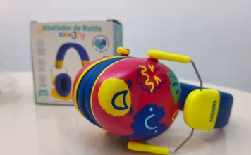 Criciúma entrega 500 abafadores de ruído para escolas Fotografia em close-up de um abafador de ruído infantil com design colorido em tons de vermelho, azul e amarelo, decorado com desenhos lúdicos. Ao fundo, em desfoque, aparece a embalagem do produto. O equipamento é um dos 500 dispositivos distribuídos pelo Governo de Criciúma para apoiar a inclusão de estudantes com hipersensibilidade auditiva na rede municipal de ensino.