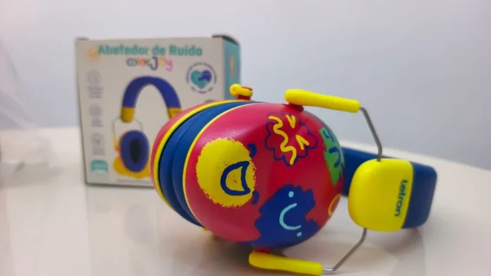 Criciúma entrega 500 abafadores de ruído para escolas Fotografia em close-up de um abafador de ruído infantil com design colorido em tons de vermelho, azul e amarelo, decorado com desenhos lúdicos. Ao fundo, em desfoque, aparece a embalagem do produto. O equipamento é um dos 500 dispositivos distribuídos pelo Governo de Criciúma para apoiar a inclusão de estudantes com hipersensibilidade auditiva na rede municipal de ensino.
