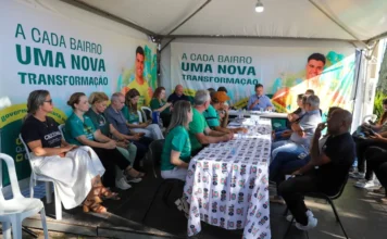 Criciúma inicia Gabinete Itinerante na Cidade Mineira Encontro de escuta ativa do Gabinete Itinerante da Prefeitura de Criciúma na região da Cidade Mineira. Prefeito Vagner Espindola, microfone na mão, lidera diálogo com moradores sob tenda. Banners com a frase 'A Cada Bairro Uma Nova Transformação' são visíveis.