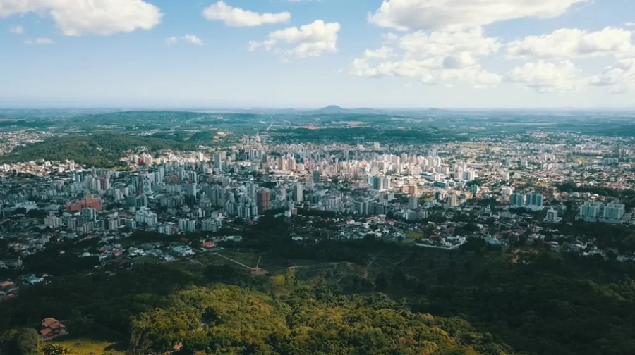 Uma vista aérea panorâmica de Criciúma, com destaque para o seu denso centro urbano de prédios e o potencial econômico e empresarial da cidade, onde a prefeitura propõe a redução do ITBI para empresas que regularizarem imóveis.