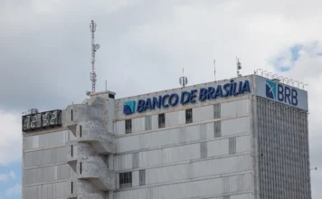 DF aprova aporte de R$ 6,6 bi no BRB para cobrir rombo Imagem da fachada lateral de um edifício de cor cinza onde se lê, no topo, o letreiro "BANCO DE BRASÍLIA" ao lado da logomarca e da sigla BRB. A foto, tirada sob um céu nublado, identifica a sede da instituição financeira que recebeu autorização da Câmara Legislativa do Distrito Federal para um aporte de até R$ 6,6 bilhões para cobrir prejuízos financeiros.