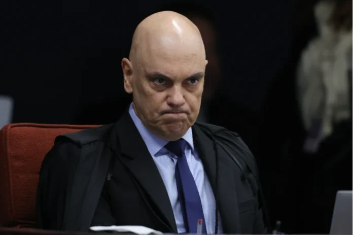 Dallagnol e Chiquini devem pedir impeachment de Moraes O ministro do Supremo Tribunal Federal, Alexandre de Moraes, é visto em um plano médio, sentado em sua cadeira no plenário. Ele veste a toga preta oficial, possui expressão séria e direciona o olhar para frente durante uma sessão.