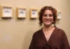Elisa Corrêa abre mostra “Ensaio sobre Coleções” na Unesc A artista visual Elisa Corrêa sorri em frente a quatro quadros com molduras claras contendo desenhos detalhados de mariposas em grafite, durante a abertura da exposição "Ensaio sobre Coleções" no Espaço Cultural Unesc.