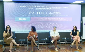 Evento na Alesc incentiva o empreendedorismo feminino Painel de debates com quatro mulheres sentadas no palco do Plenarinho da Alesc durante o evento Sororidade a Sério Edição 2023. O telão de fundo exibe o título do evento, a data 27.03 e a frase 'Um evento de mulheres para mulheres'. Mulheres brancas e negras compõem a mesa, com uma delas falando ao microfone. Foco em empreendedorismo feminino e liderança.